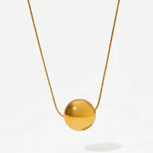 Close-up of minimalist gold plated hollow sphere pendant with high polish snake chain