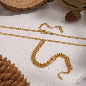 Minimalist golden beaded Y-necklace in 304 stainless steel on a natural stone base