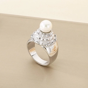 Detail of silver geometric textured ring with a white pearl on a champagne background
