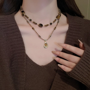 Close-up of double-layer beaded necklace with sun and star pendant on a model
