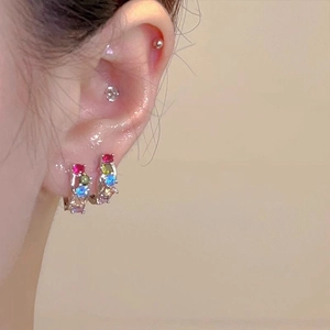 Close-up of model wearing colorful zircon huggie earrings with rainbow gemstone inlay