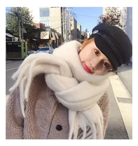 Close-up of fluffy white scarf with thick braided tassels worn with a black beret