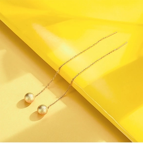 Detail of 18K gold titanium heart tassel earrings with a refined matte texture finish