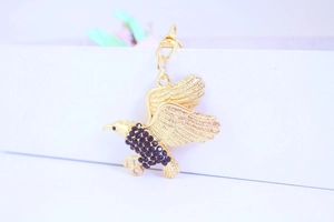 Makroaufnahme des goldenen Adler-Schlüsselanhängers mit schwarzen Strasssteinen und Flügeln