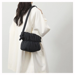 Close-up of black quilted cloud bag with padded texture on model's shoulder