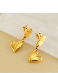 Macro shot of gold-plated heart earrings featuring LOVE engraving on titanium steel
