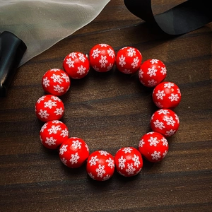 Vue macro de 13 perles en bois rouges avec motifs flocons de neige sur bracelet festif