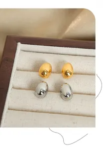 Close-up of gold and silver oval stud earrings in a wooden jewelry gift box
