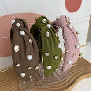 Close-up of knot headbands in brown, green, and pink fabric with pearls and rhinestones