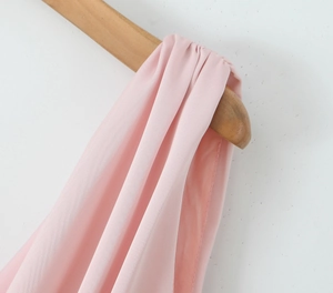 Détail d'une robe rose sans manches sur cintre montrant la texture du tissu de qualité