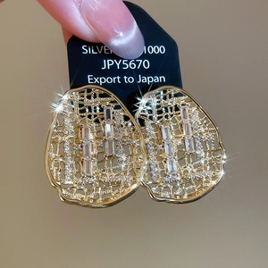 Vue macro de boucles d'oreilles ovales plaquées or avec zircons cubiques sur carte noire