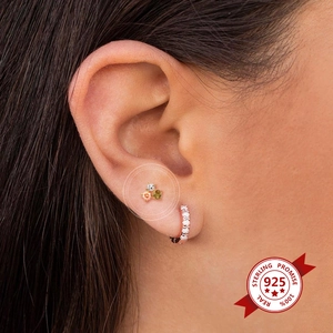 Detail of 925 sterling silver stud earring with colorful zircons on female ear