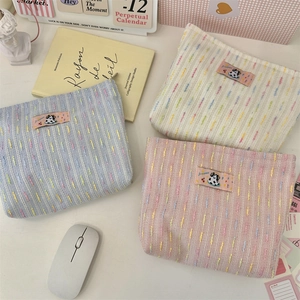 Flat lay of colorful woven makeup bags with dog patches and zipper closures