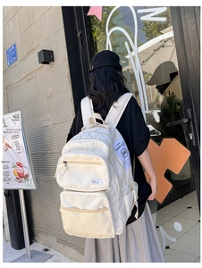 Rear view of large capacity cream backpack featuring multi-pocket design on outdoor model