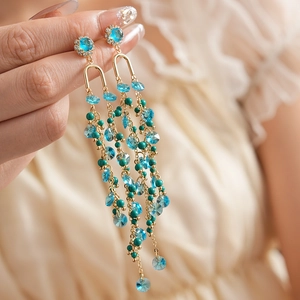 Macro view of gold tassel earrings with turquoise beads and blue crystals detail