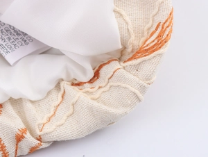 Detail of embroidered beige jacket showing wash care label and textured fabric surface