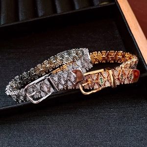 Close-up of gold and silver belt buckle bracelets with pavé diamonds in a luxury gift box
