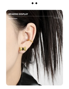 Close-up of golden bow earring with black stone and chain ear cuff worn by model