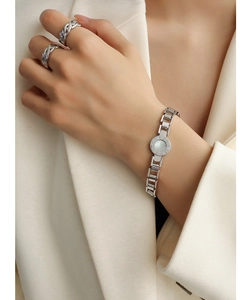 Detailed view of women's roman numeral charm bracelet with white mother of pearl inlay