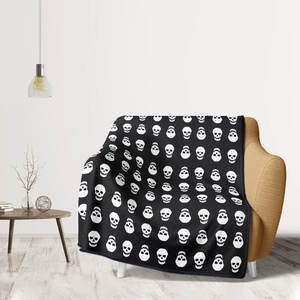 Close-up of black flannel blanket featuring detailed white gothic skull patterns on a sofa