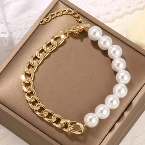 Detailed close-up of Baroque pearl bracelet with golden chain links on jewelry box