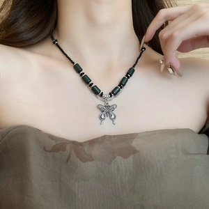 Detailed shot of Chinese style ceramic butterfly necklace with black beads and green accents