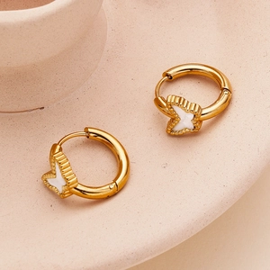 Golden stainless steel hoop earrings with white enamel butterfly on a ceramic tray