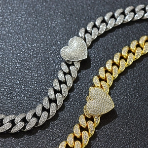 Vista macro di bracciali cubani oro e argento con pendenti a cuore ghiacciati
