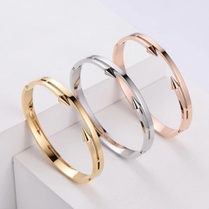 Detailed view of polished dual-stud bangles in gold, silver, and rose gold finishes