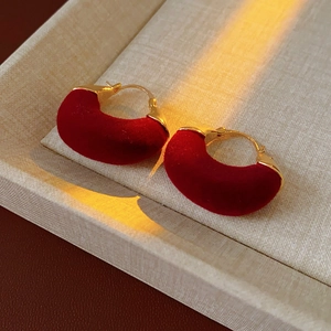 Macro shot of red velvet U-shaped earrings with gold-plated metal clasp for women