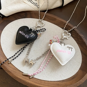 Detailed macro view of heart leather pendant with metal bow and unique tooth charm