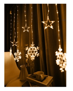 Detail of warm white LED curtain lights with star and snowflake ornaments for bedroom decor