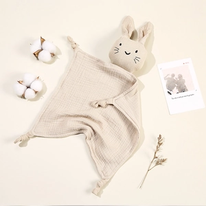 Detail of beige cotton muslin bunny security blanket with cute embroidered face and knotted corners
