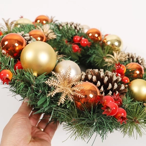 Christmas wreath with gold plating balls, red berries and natural pine cones on pine needles