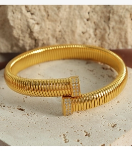 Macro shot of gold Tubogas cuff bracelet with micro-pave zircon on stone surface