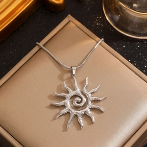 Detail of silver hollow sun pendant necklace on beige jewelry box with sleek snake chain