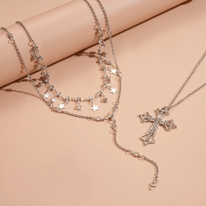Detail of layered silver necklaces featuring rhinestone cross and star tassel pendants