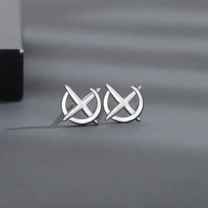 Detailed macro view of silver cross ring earrings with vintage rhinestones on grey background