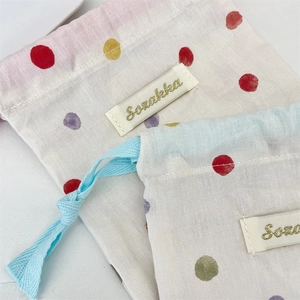Détail du sac à cordon en coton avec pois colorés et étiquette Sozakka brodée