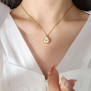 Detail of gold teardrop pendant with crown motif and white shell inlay on model
