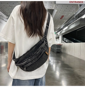 Detailed back view of a washed denim sling bag with multiple zip pockets on a male model