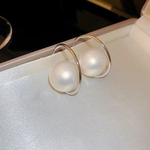 Macro shot of elegant silver hoop earrings featuring a large lustrous white pearl accent