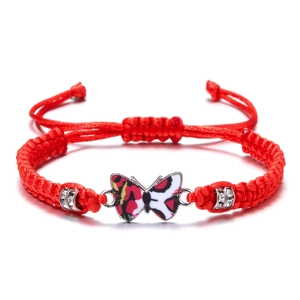 Detail of red braided cord bracelet featuring enamel butterfly charm and rhinestone beads