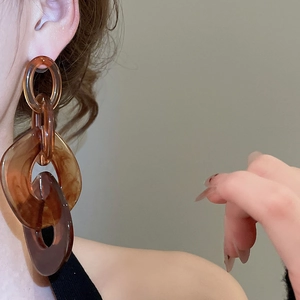 Close-up of amber acrylic link earrings showing texture and chain design on model