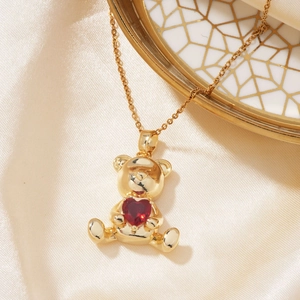 Close-up of golden bear pendant with red heart zircon on elegant silk background