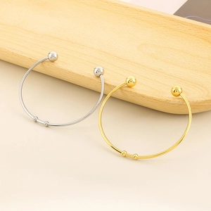 Detailed view of minimalist gold and silver open bracelets on a light wood tray