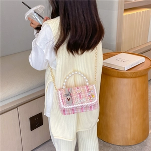 Pink tweed kids crossbody bag with pearl handle and charms shown in a lifestyle setting