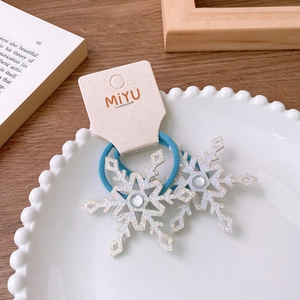 Detail of blue glitter snowflake hair clips for girls on a white ceramic plate