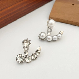 Detalle de elegantes pendientes asimétricos con perlas de imitación y piedras de strass