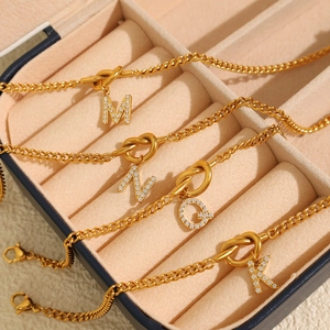 Elegante goldene Buchstaben-Halsketten mit Zirkonia in einer beigen Schmuckschatulle